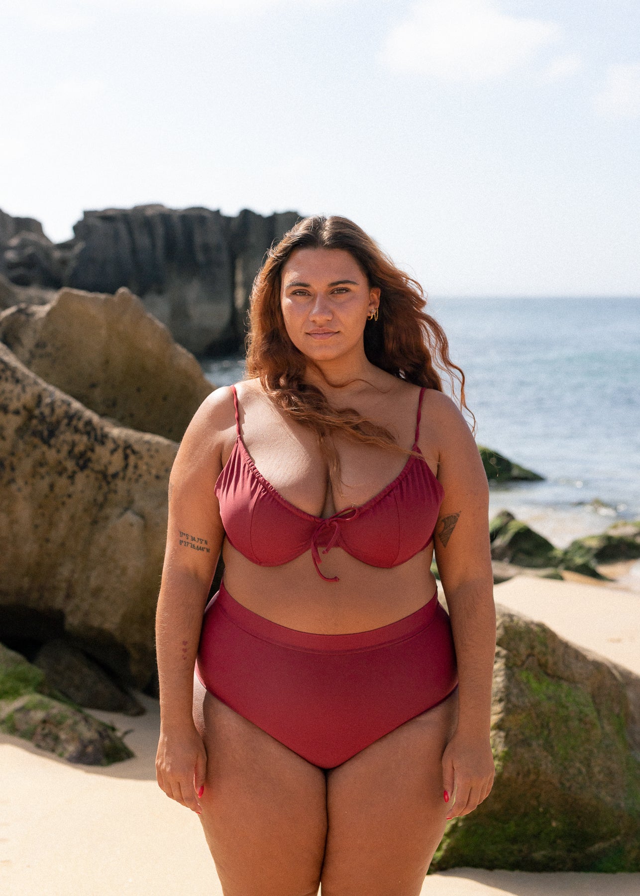 Burgundy drawstring top by Lilja the Label worn with matching bottoms on a beach setting.
