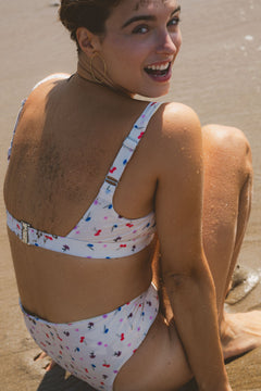 Floral print bikini top by Lilja the Label with adjustable straps, shown with gold hoop earrings.