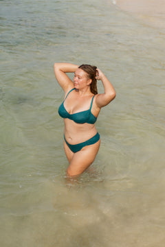 Teal gathered top with ruched front and thin straps, worn in shallow water, lifestyle view